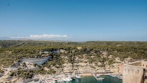Un paysage côtier avec un port de plaisance, des bateaux et un bâtiment à la façade en pierre.