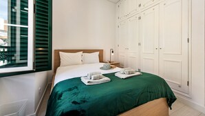 Een hotelkamer met een bed, een kledingkast en een raam met jaloezieën.