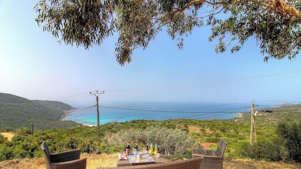 Une table dressée à l’extérieur, avec des bouteilles et des verres, donnant sur un paysage côtier.