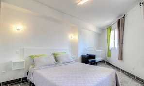A bedroom with a bed, bedside tables, a crib, and a window with curtains. - Aja puzzuta - COTI CHIAVARI (COTI CHIAVARI)