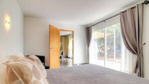 Une chambre dotée d’un grand lit, d’une télévision et d’une porte-fenêtre coulissante donnant sur une terrasse.