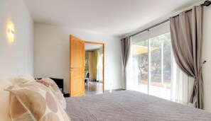 Un dormitorio con una cama grande, televisión y puerta corrediza de vidrio que da a un patio.