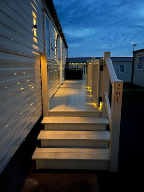 A wooden staircase leading to a covered porch with a railing, adjacent to a mobile home. - Bang Tidy 261 - Cabin - Wifi - Pool - Sleep 6 (Paignton)