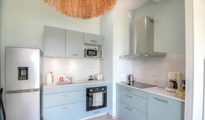 Eine moderne Küche mit Kühlschrank, Mikrowelle, Backofen und Kaffeemaschine.