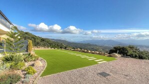 Ein angelegter Garten mit Rasen, Kiesweg und Blick auf ferne Berge.