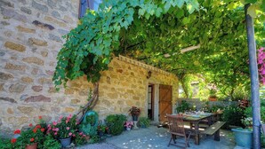 A stone building with a covered patio, outdoor seating, and potted plants. - Vacations with family and friends in the countryside (ECCICA SUARELLA)