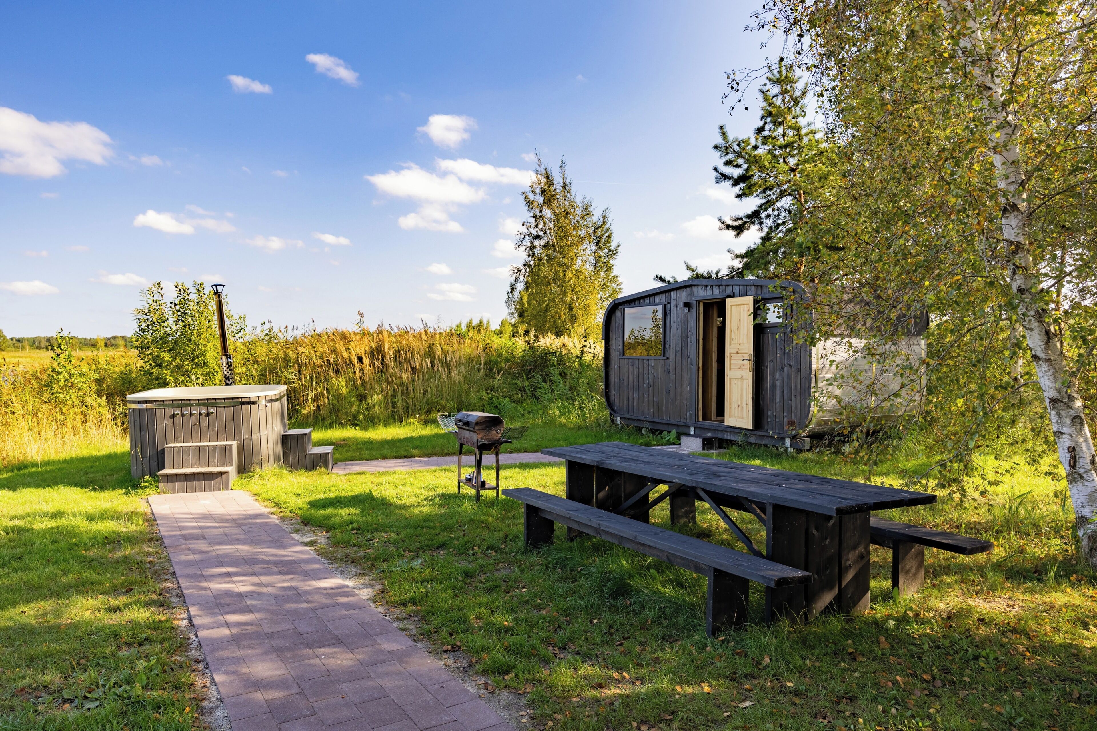 A rustic outdoor setting with a wooden cabin, a picnic table, and a barbecue grill.