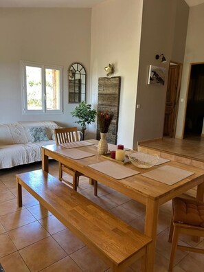 A dining area with a wooden table, benches, and a sofa. - Swimming pool, comfort and unspoilt surroundings: everything you need to discover the far south is here. (MONACIA D'AULLENE)