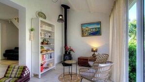 A cozy living room with a bookshelf, a painting, wicker furniture, and a view through a window. - CasaNina - BORGO - Guest house (BORGO)