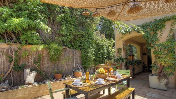 An outdoor dining area with a table set for two, surrounded by potted plants and a bamboo fence. - Casa Baghjuccia - CARGESE (CARGESE)