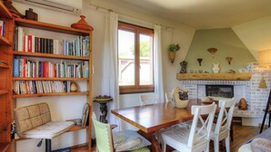 A cozy living room with a fireplace, a bookshelf, and a dining area. - Casa Baghjuccia - CARGESE (CARGESE)