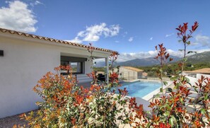 Eine moderne Villa mit Swimmingpool, Sitzgelegenheit im Freien und Bergblick.
