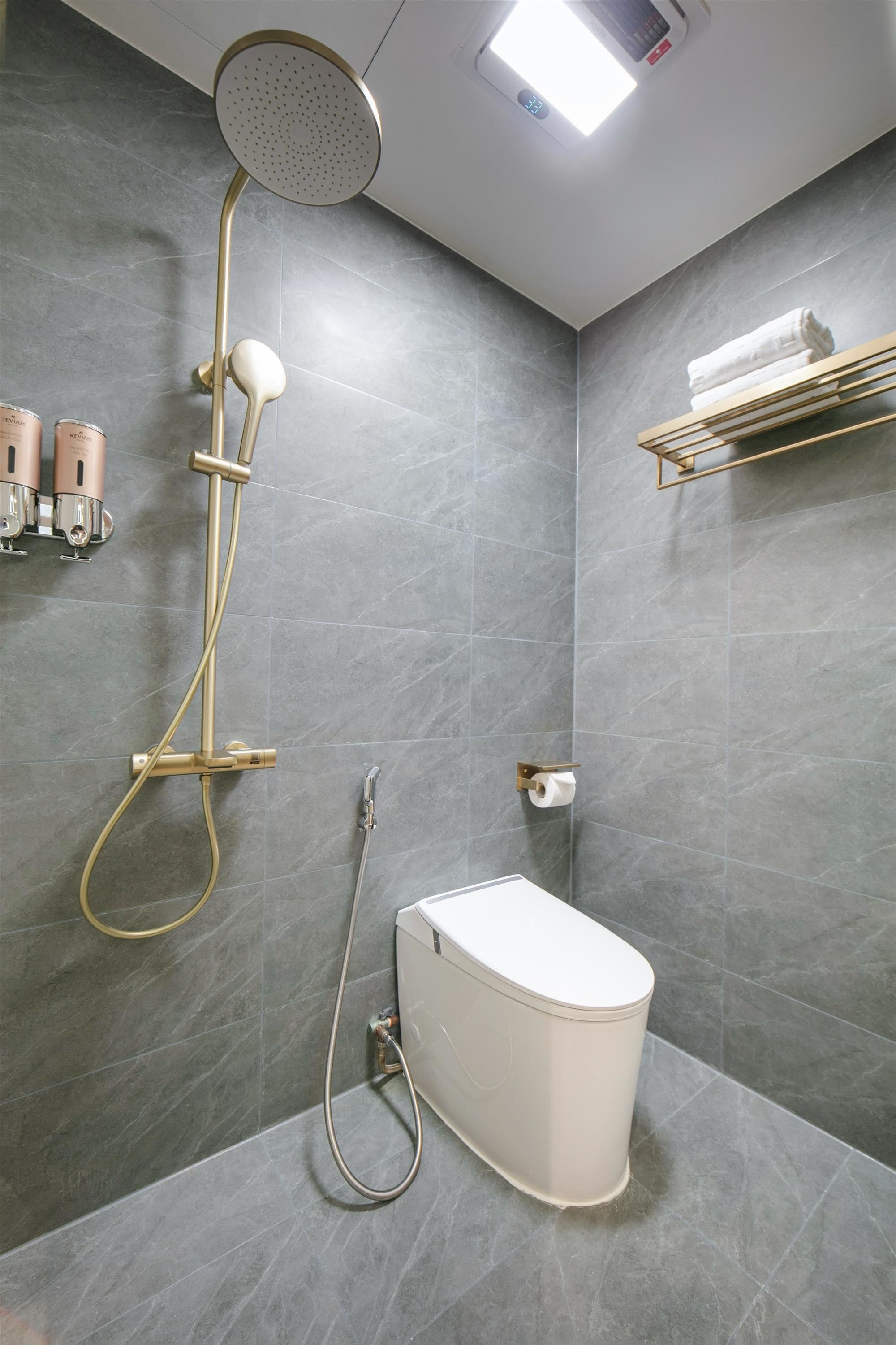 A modern bathroom with a shower, toilet, and towel rack.