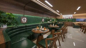 A restaurant with green upholstered booths, wooden tables, and chairs.