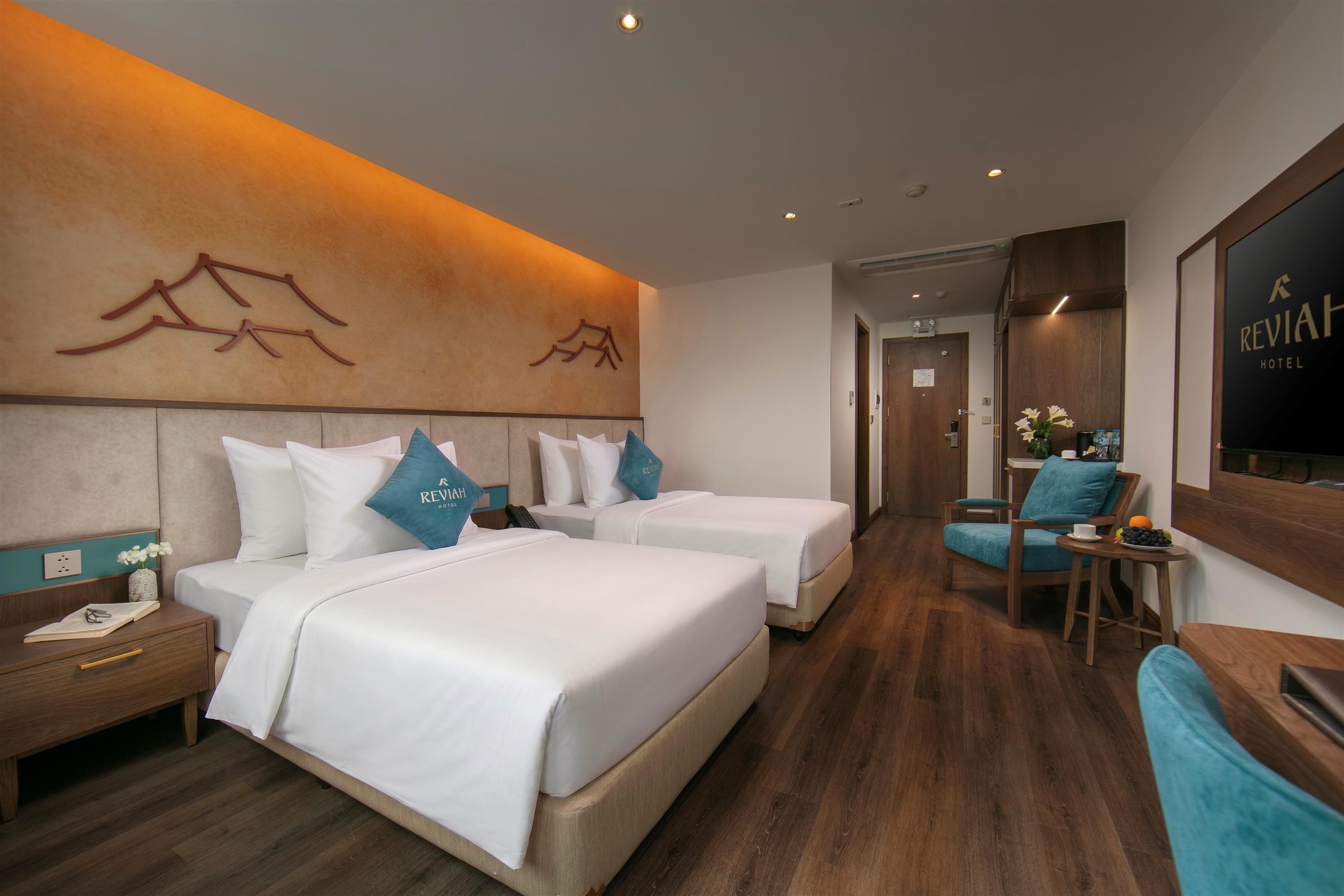 Habitación de hotel con dos camas, un escritorio, una silla y un televisor.