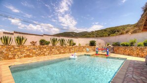 A swimming pool with a stone wall, surrounded by plants and a view of hills. - Calm - VIGGIANELLO - Gîte (VIGGIANELLO)