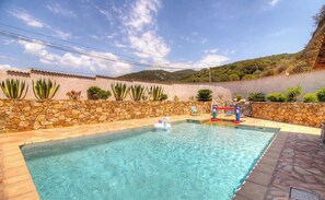A swimming pool with a stone wall, surrounded by plants and a view of hills. - Calm - VIGGIANELLO - Gîte (VIGGIANELLO)