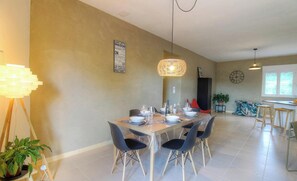 A dining area with a table set for four, a hanging light fixture, and a clock on the wall. - Calm - VIGGIANELLO - Gîte (VIGGIANELLO)