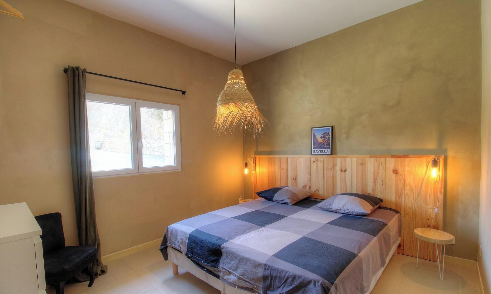 A bedroom with a bed, a window, a hanging light fixture, and a wooden headboard.