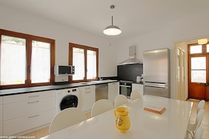 A modern kitchen with built-in appliances, a dining table, and a yellow pitcher. - I Monti Signori - OTA (OTA)