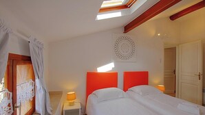 Ein Hotelzimmer mit zwei Betten, einem Oberlicht, einer Wanddekoration und einer Tür.