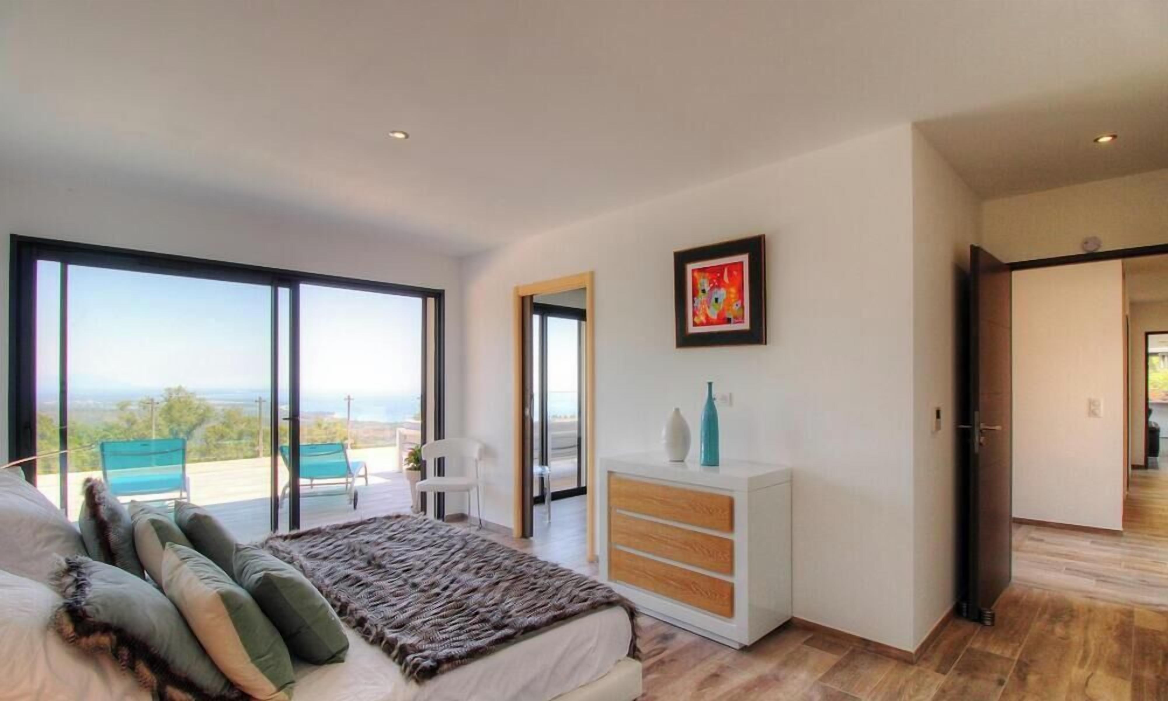Quarto com cama, cómoda, cadeira e uma janela grande.