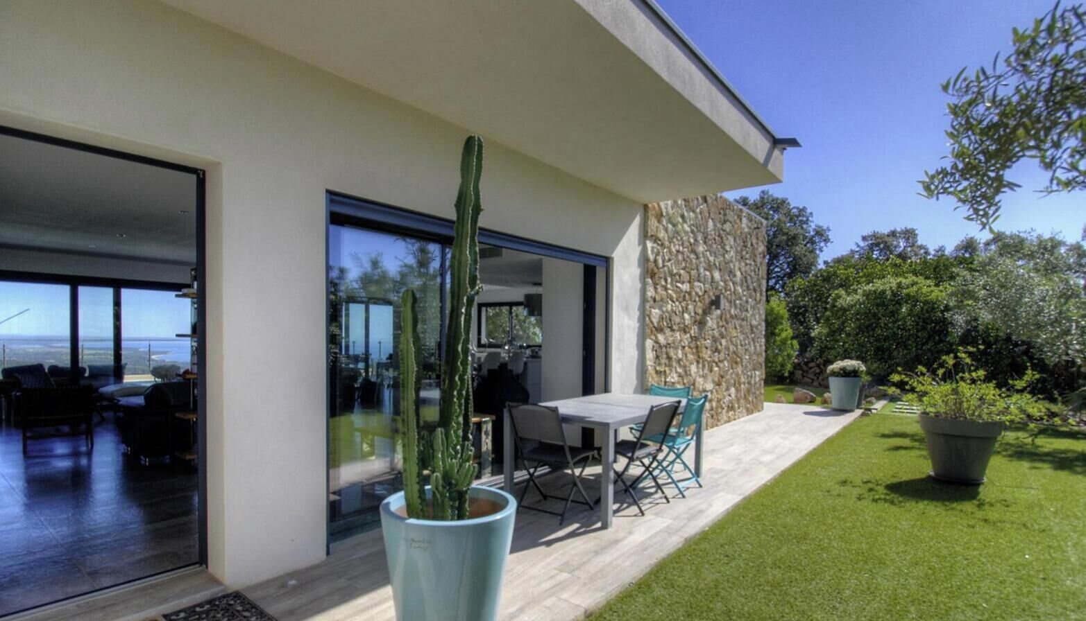 Une maison moderne dotée d’un patio, d’un cactus et offrant une vue sur l’océan.