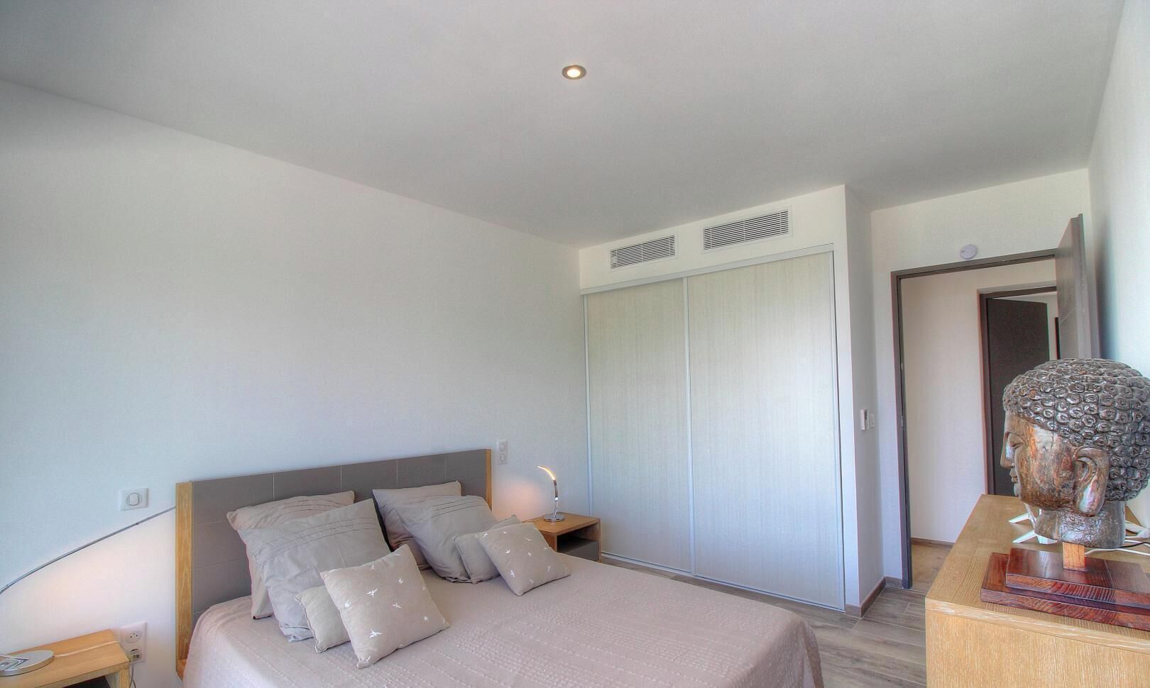 Ein Schlafzimmer mit einem Bett, Nachttischen, einem Kleiderschrank und einer Zierbüste.