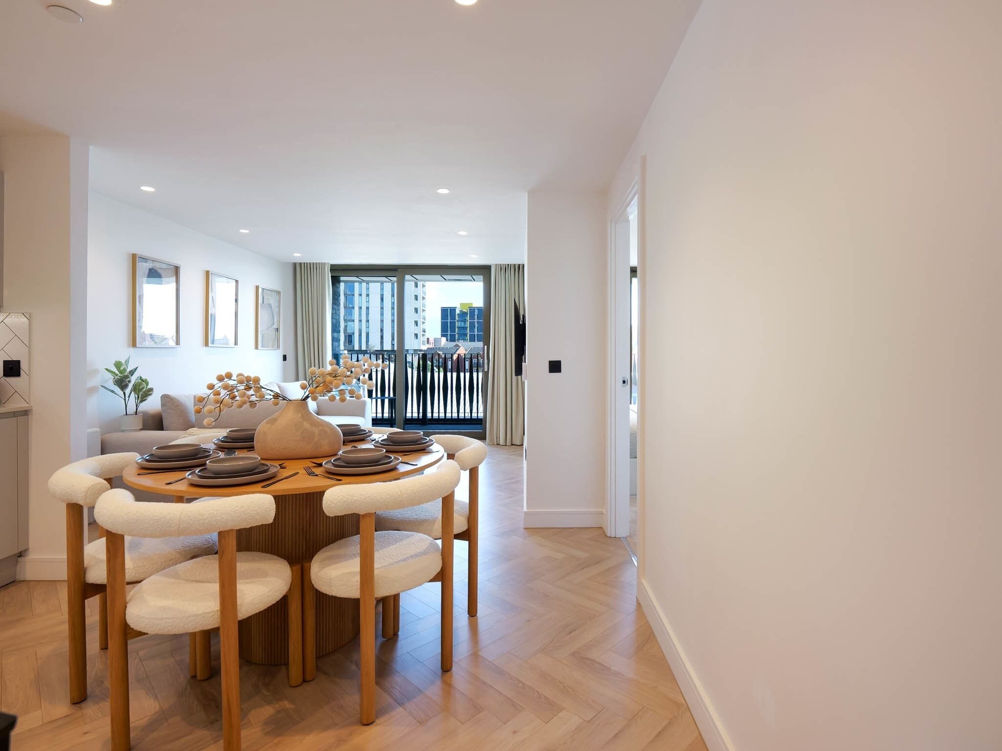Un espace repas moderne avec une table ronde, des chaises et un vase de fleurs.