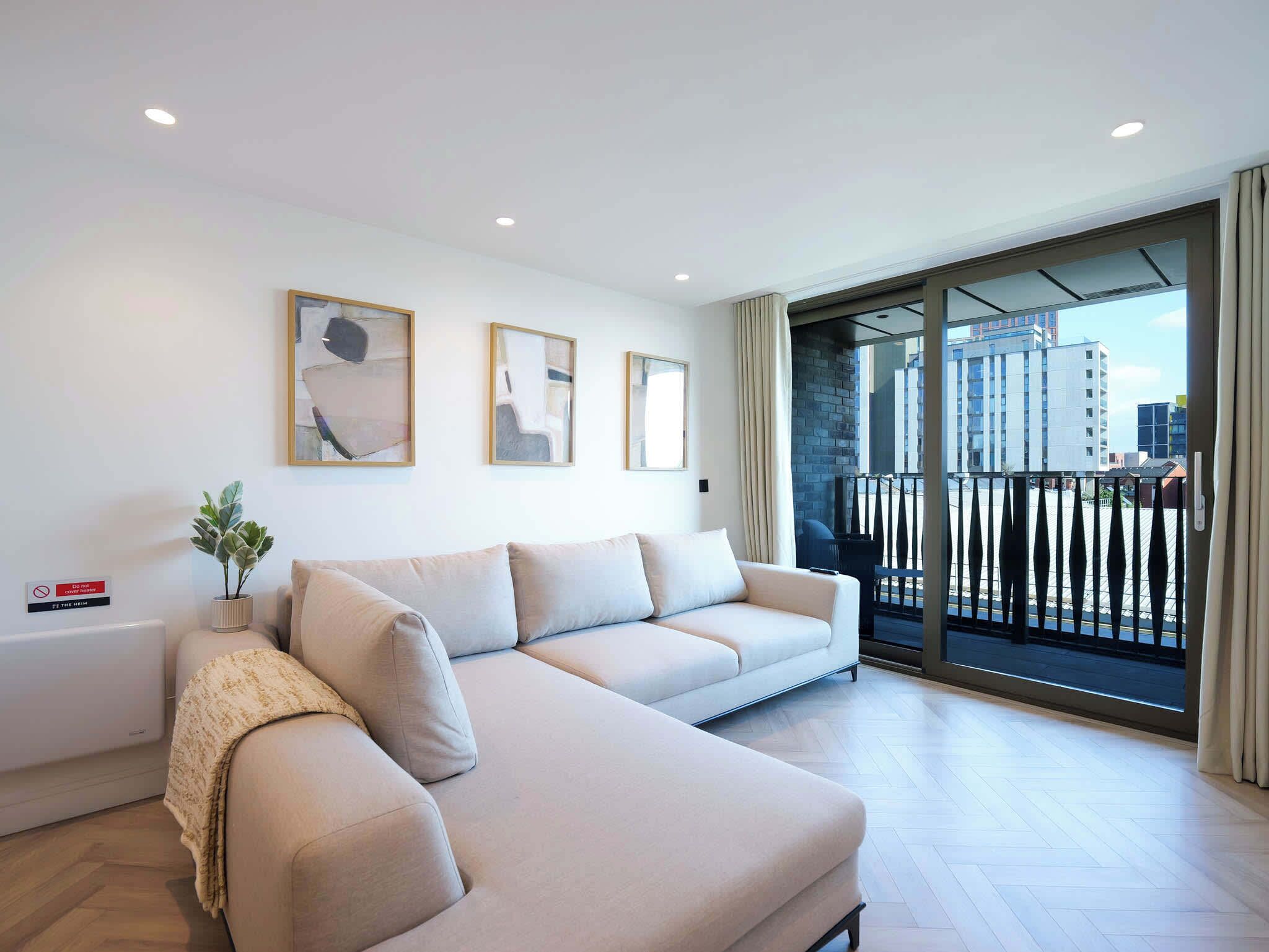 A modern living room with a sofa, a potted plant, and artwork on the wall.