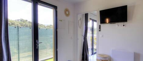 Une chambre avec un lit, une télévision, un radiateur et une porte-fenêtre coulissante donnant sur un espace extérieur.