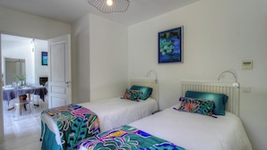 A room with two beds, a dining area, and a painting on the wall. - Villa Loulou - BONIFACIO (BONIFACIO)