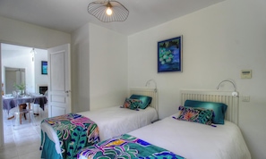 Ein Zimmer mit zwei Betten, einer Essecke und einem Gemälde an der Wand.