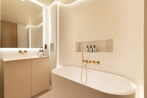 A modern bathroom with a freestanding bathtub, a vanity with a mirror, and a shelf with toiletries. - A Wonderfull 1-BR w/ Services - Champs Elysées (Paris)