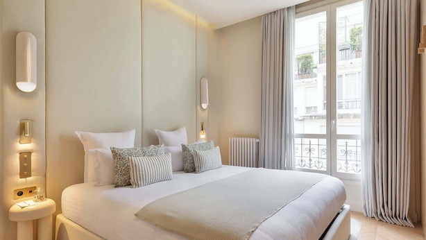 Un dormitorio moderno con una cama grande, mesitas de noche, apliques de pared y vistas al exterior.