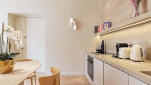 Una cocina moderna con encimera de madera, electrodomésticos blancos y una orquídea en maceta sobre la mesa.