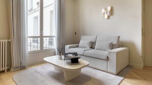 Una sala de estar moderna con un sofá, una mesa de centro y una ventana con cortinas.