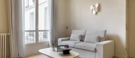 Una sala de estar moderna con un sofá, una mesa de centro y una ventana con cortinas.