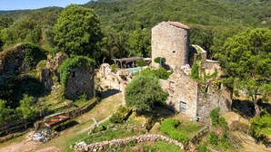 Una torre in pietra con piscina e gazebo in un paesaggio montuoso e rigoglioso.