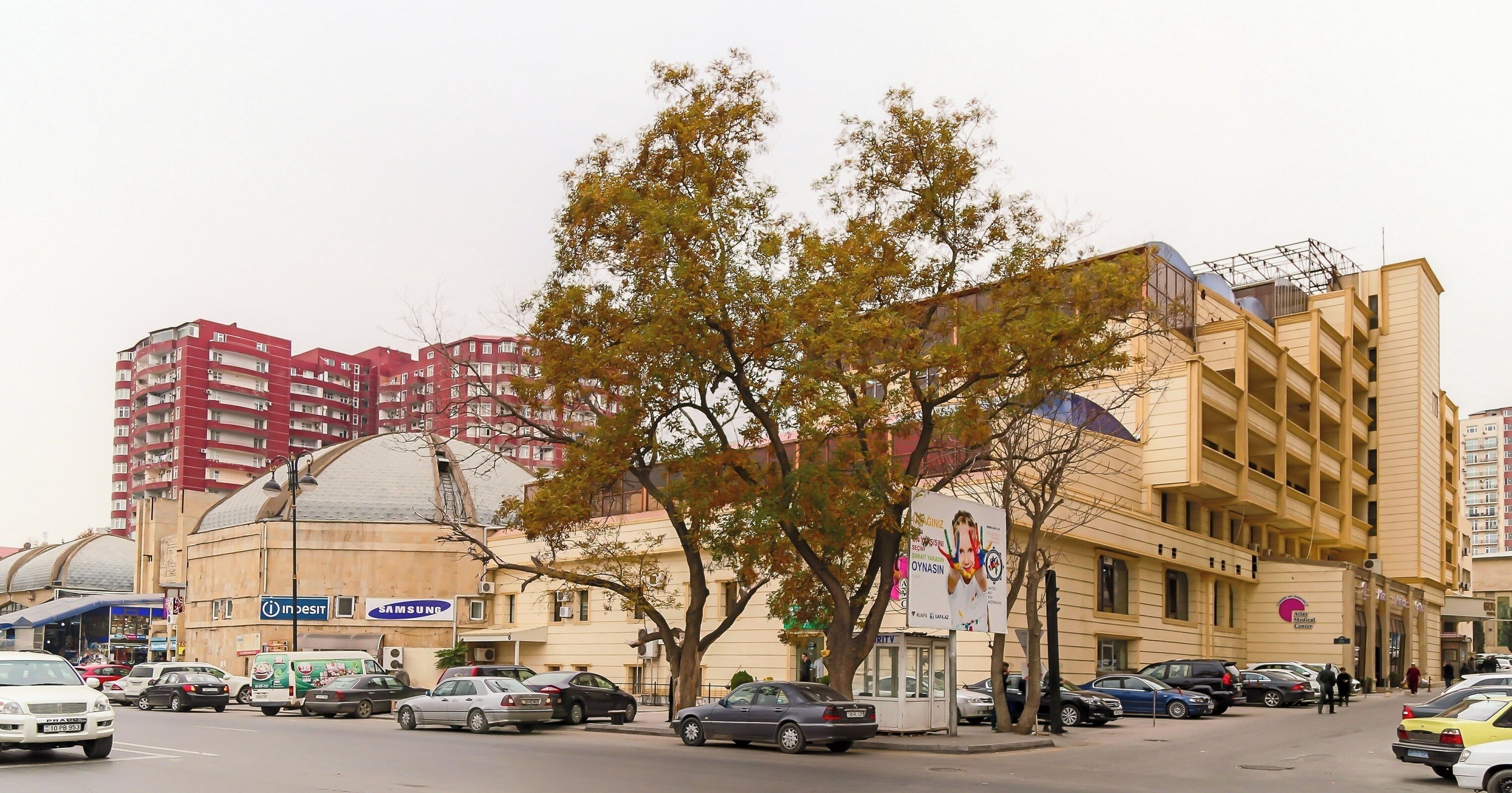 A multi-story building with a large dome structure, a Samsung store, and a bus stop.