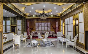 Una habitación lujosa con candelabro, asientos mullidos y suelo estampado.