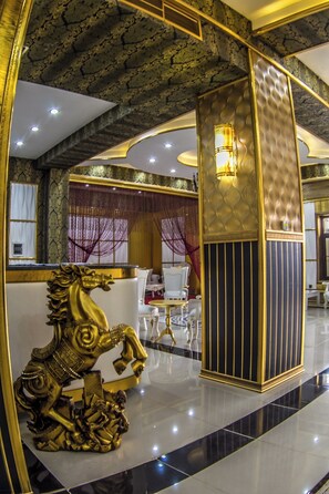 Un interno lussuoso con una scultura decorativa a forma di cavallo dorato, arredi eleganti e un soffitto a motivi.
