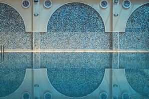 Una piscina con un muro piastrellato decorato con motivi circolari e un riflesso limpido.