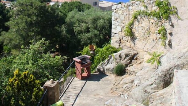 Una terraza con sillas y una pequeña mesa con vista a un paisaje costero.