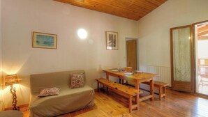 A cozy room with a wooden ceiling, a sofa with cushions, a wooden dining table with benches, and a door with a frosted glass panel. - Cricheto 1 - BASTELICA (BASTELICA)