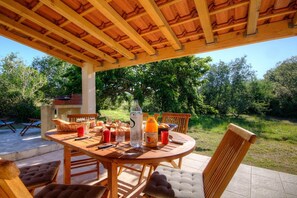 An outdoor wooden table with chairs, a bottle of orange juice, and a basket of bread. - U Pagliaghju - SPELONCATO (SPELONCATO)