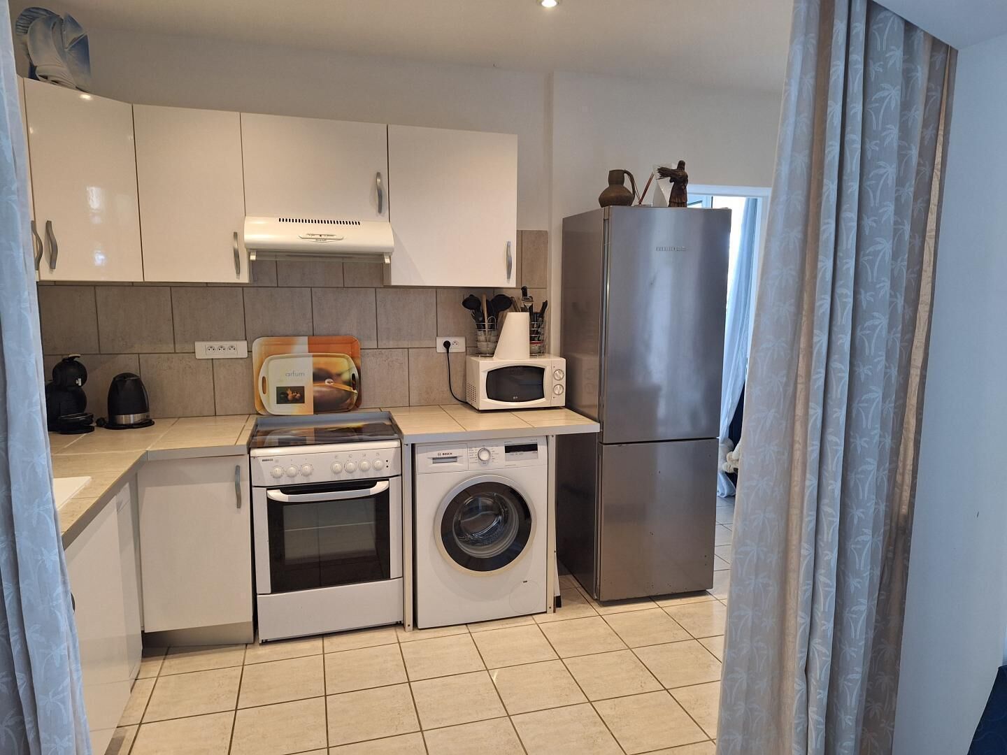 A compact kitchen with a stove, microwave, oven, and washing machine.