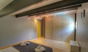 A modern bedroom with a bed, a wooden wardrobe, and a small bedside table. - Villa Orsu - SAINTE LUCIE DE PORTO VECCHIO (SAINTE LUCIE DE PORTO VECCHIO)