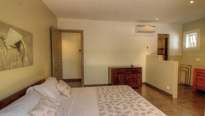 Un dormitorio con cama, cómoda de madera, espejo y equipo de aire acondicionado.