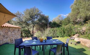 A patio with a stone wall, a table with chairs, and a grill. - Petralonga sheepfold (SOTTA)